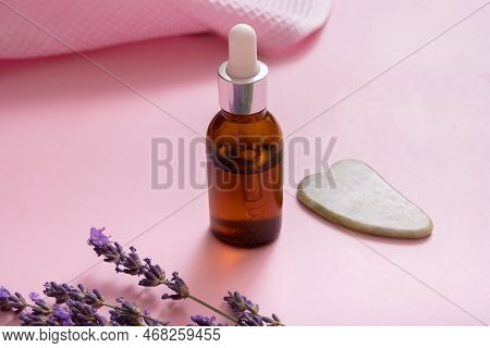 Dropper Bottle And Face Skin Massager With Lavender Flowers On Colored Background