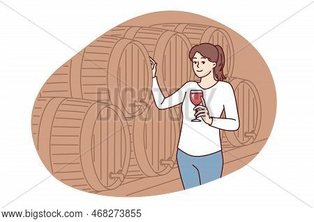 Woman With Glass Of Wine Stands Near Wooden Barrel For Tincture Of Alcoholic Drink And Looks At Scre