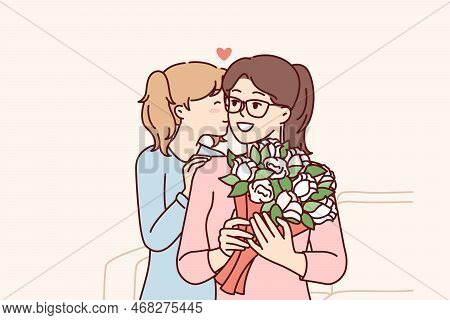 Loving Teenage Girl Gives Flowers To Mom On Eve Of Eighth Of March Or Mother Day. Child Kisses Woman