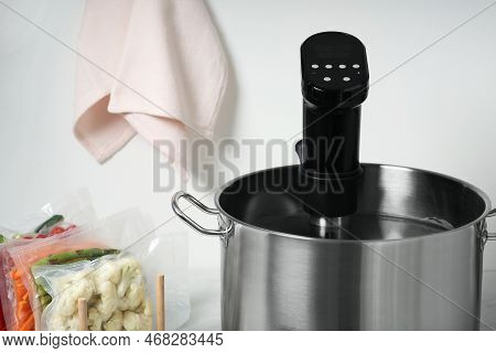 Pot With Sous Vide Cooker And Vacuum Packed Food Products, Closeup. Thermal Immersion Circulator