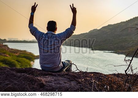 Isolated Young Man Sitting At Mountain Top With Lake View From Flat Angle