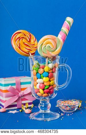 Colorful Candies In Cup On Table On Light Background Background. Large Swirled Lollipops. Creative C