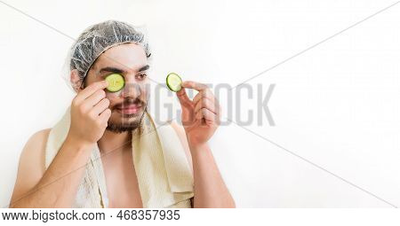 A Young Man In A Face Mask And Cucumbers In A Beauty Salon. Facial Treatment Concept.