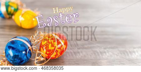Happy Easter Calligraphy Text Message With Colorful Decorated Eggs Over Rustic Wooden Background.