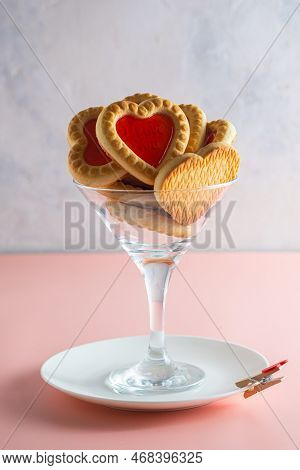 Heart-shaped Cookies With Jam Filling In A Martini Glass On A Pink Plain Background. Valentine's Day