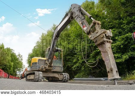 Excavator With Hydraulic Jack Hammer  Breaking Asphalt In Preparation For Drainage Works Close Up An