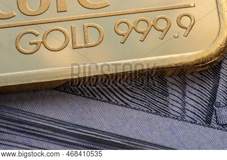 Minted Gold Bar 999.9, Fineness Against The Background Of A Dollar Bills.