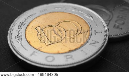 Hungarian Coin Of 100 Forints Lies On Dark Black Surface Close Up. Money Of Hungary. News About Econ