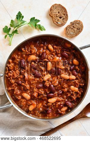Stewed Beans With Ground Beef, Jalapeno Pepper And Bacon In Cooking Pan Over Light Stone Background.