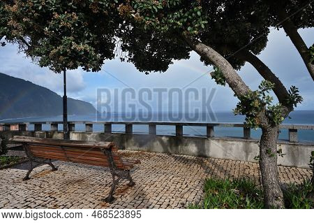 Empty Bench At Atlantic Ocean Coast, Rainbow Over Ocean, Madeira Island
