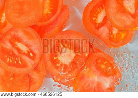 Close-up View Of The Red Tomato Slices In Water Background. Texture Of Cooling Vegeteble Drink With