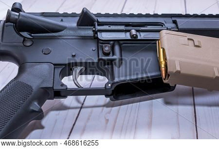 An Ar15 Rifle Chambered In 223 Caliber With A Loaded Magazine Next To It On A White Wooden Backgroun