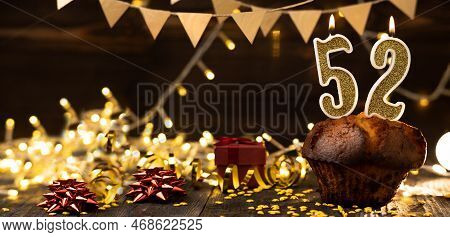 Number 52 Golden Festive Burning Candles In A Cake, Wooden Holiday Background. Fifty-two Years Since