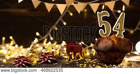Number 54 Golden Festive Burning Candles In A Cake, Wooden Holiday Background. Fifty-four Years Sinc