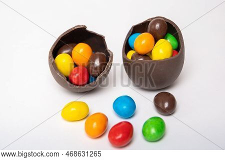 Cracked Chocolate Easter Eggs Full Of Colorful Small Round Candies On A White Background With Colorf