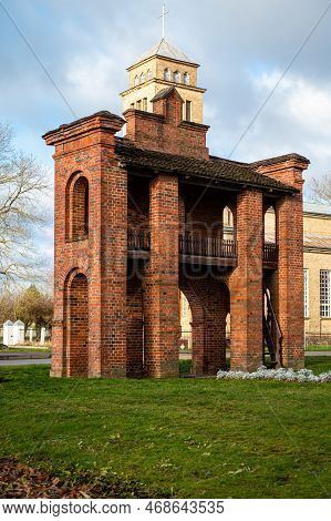 Old Catholic Church And Red Brick Gates In City Akniste, Latvia. Aknistes Visual Identity Symbol.