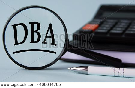 Dba ( Doing Business As) - Acronym On Magnifying Glass On A Light Background With Calculator, Notepa