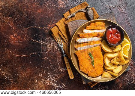 Breaded German Weiner Schnitzel With Potato Wedges. Dark Background. Top View. Copy Space.