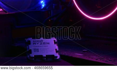 Close-up Of An Amd Ryzen 9 3900X Processor, Against The Backdrop Of Coolers With Light.