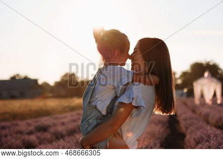 Family Day. Young Mom And Little Daughter Enjoy Relaxing In A Field With Lavender At Sunset. A Beaut