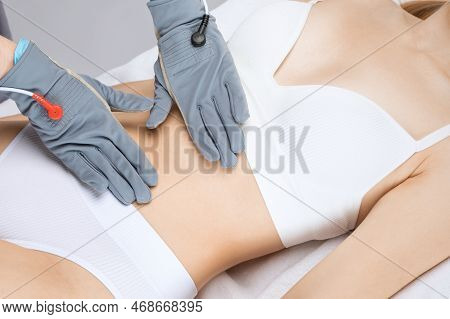 Doctor Cosmetologist Makes A Microcurrent Massage Procedure On The Belly Of A Beautiful Girl In A Be