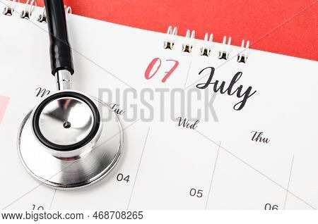 Stethoscope Medical And July 2023 Desk Calendar On The Red Background, Schedule To Check Up Healthy 