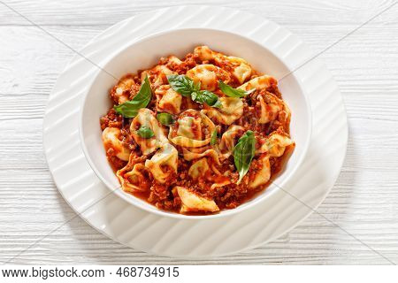 Tortellini In Ground Beef Tomato Sauce In White Bowl On White Wood Table, Horizontal View