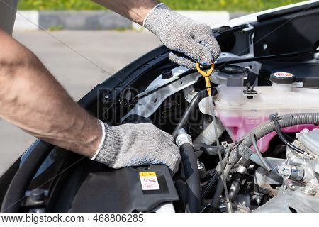 The Driver Checks The Oil Level In The Car Engine. Master Holding Oil Dipstick. Hand Holding Oil Dip
