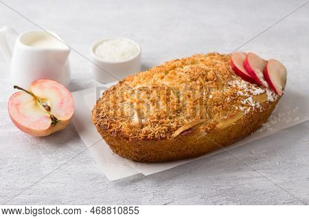 Coconut Cake, Mannik With Apples And Cream In A Ceramic Baking Dish On A Light Gray Textured Backgro