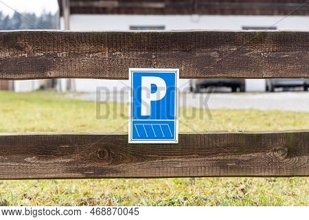 The Parking Place For Cars And The Blue Sign On The Wooden Fence