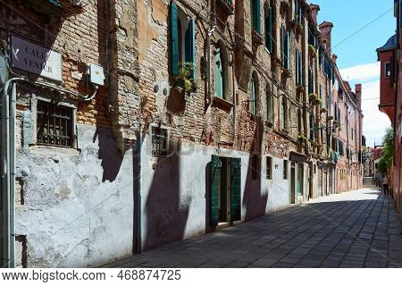 Picturesque Old Facade Of Building In Venice, Italy. Details Of Aged Brick Wall With Windows Deorate