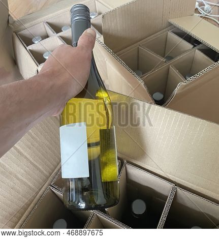 A Person Is Un Packing A Bottle Of Wine Ordered On The Internet Out Of A Delivery Box