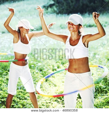 woman rotates hula hoop on nature background