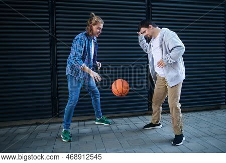 Man With Down Syndrome Playing Basketball Outdoor With His Friend. Concept Of Friendship And Integra