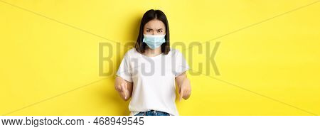 Covid-19, Pandemic And Social Distancing Concept. Disappointed Asian Girl In Medical Mask, Frowning 
