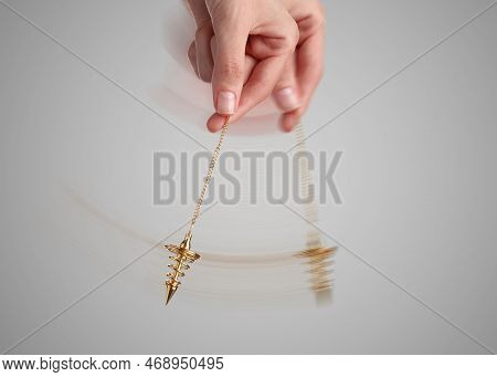 Hypnosis Session. Woman Swinging Pendant On Light Background, Closeup. Motion Effect
