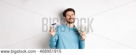 Cheerful Guy Celebrating Salary, Dancing With Plastic Credit Card And Money, Smiling Satisfied, Stan