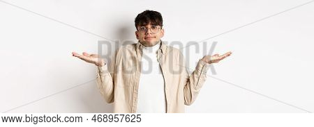 Portrait Of Handsome Young Man Looking Confused, Know Nothing, Shrugging Shoulders And Spread Hands 