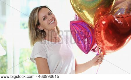 Pleased Blonde Woman Smiling And Holding Many Air Baloons In Hand. Celeprating Birthday At Home, Hap