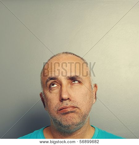 portrait of bored senior man looking up over grey background