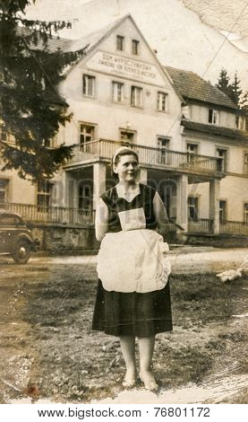 POLANICA ZDROJ, POLAND, CIRCA 1930: Vintage photo of chambermaid in front of a guesthouse