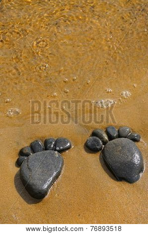  pair trace feet made of a pebble stone on the sea sand,  texture surface top view backdrop                 