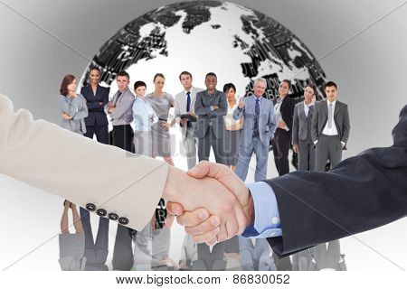 Smiling business people shaking hands while looking at the camera against white earth with business terms
