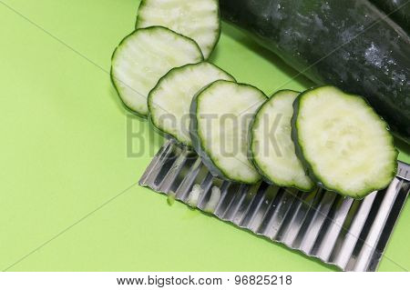 Sliced And Whole Cucamber Ordered On Top Of The Chopper On Green Background