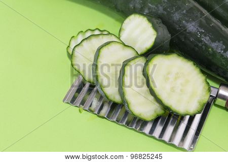 Sliced And Whole Cucamber Ordered On Top Of The Chopper On Green Background