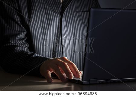 Late night internet addiction or working late man using laptop at a desk in the dark