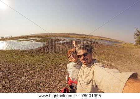 Couple taking selfie on Chobe River Namibia Botswana border Africa. Fisheye view from above toned image. Chobe National Park famous wildlilfe reserve and upscale travel destination.
