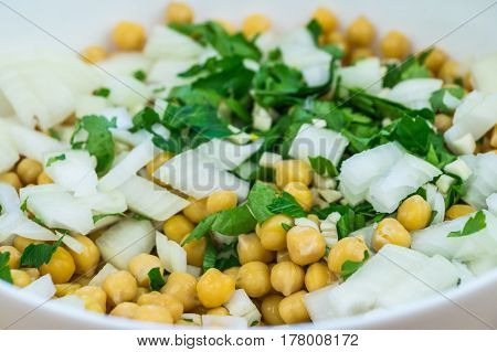 Cheakpeas, onions and leaves of parsley. Close-up image of cooked chickpeas, chopped onion, garlic and fresh parsley in bowl