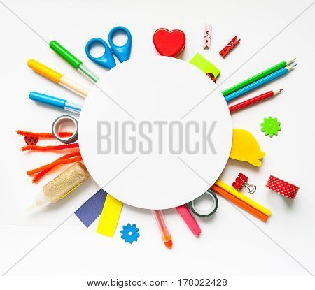 Round frame with stationery on the white background. Multicolor pencils and crayons. Place for your text.