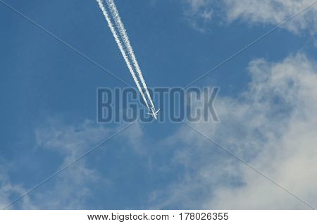 Airplane With Reaction Trail Flying Over Blue Sky With Clouds, Close Up